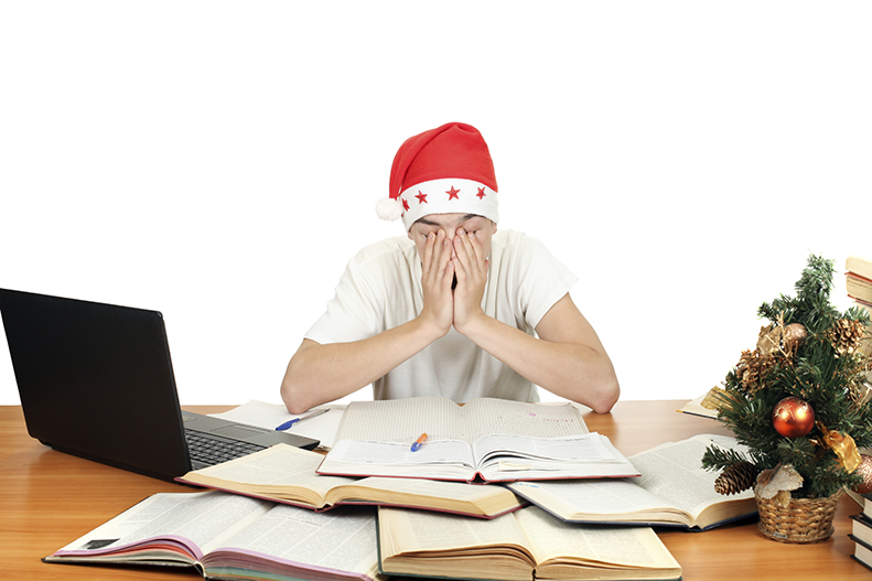 Sleepy student wearing santa hat while studying
