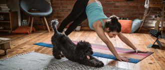 A woman stretches alongside her dog.