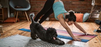 A woman stretches alongside her dog.