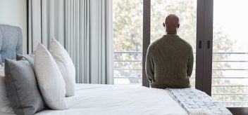 Man sitting on his bed looking out a window