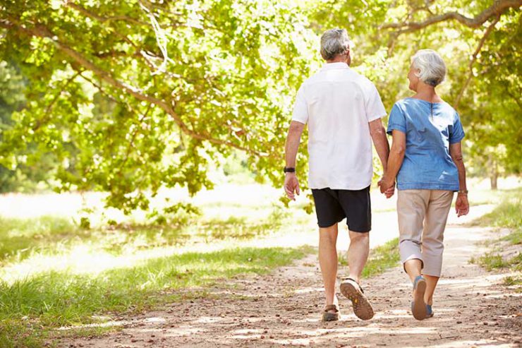 An older couple walks together in a park.