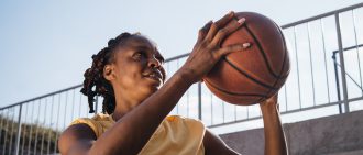 Young woman playing basketball outdoors