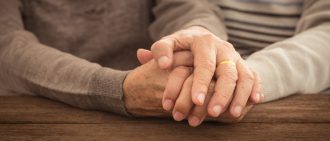 An older couple holds hands.