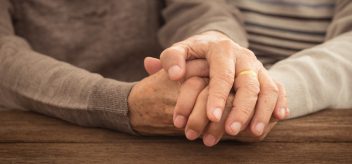 An older couple holds hands.