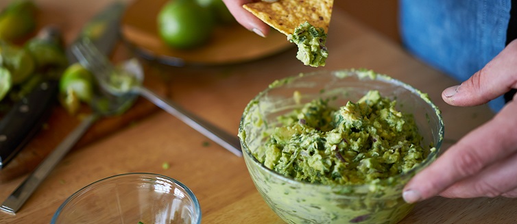 dipping a tortilla chip in guac