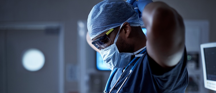 A surgeon wearing a facemask in preparation for surgery.